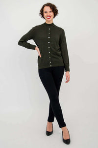 Woman models olive-green button-up sweater with black slim pants and heels, standing full body