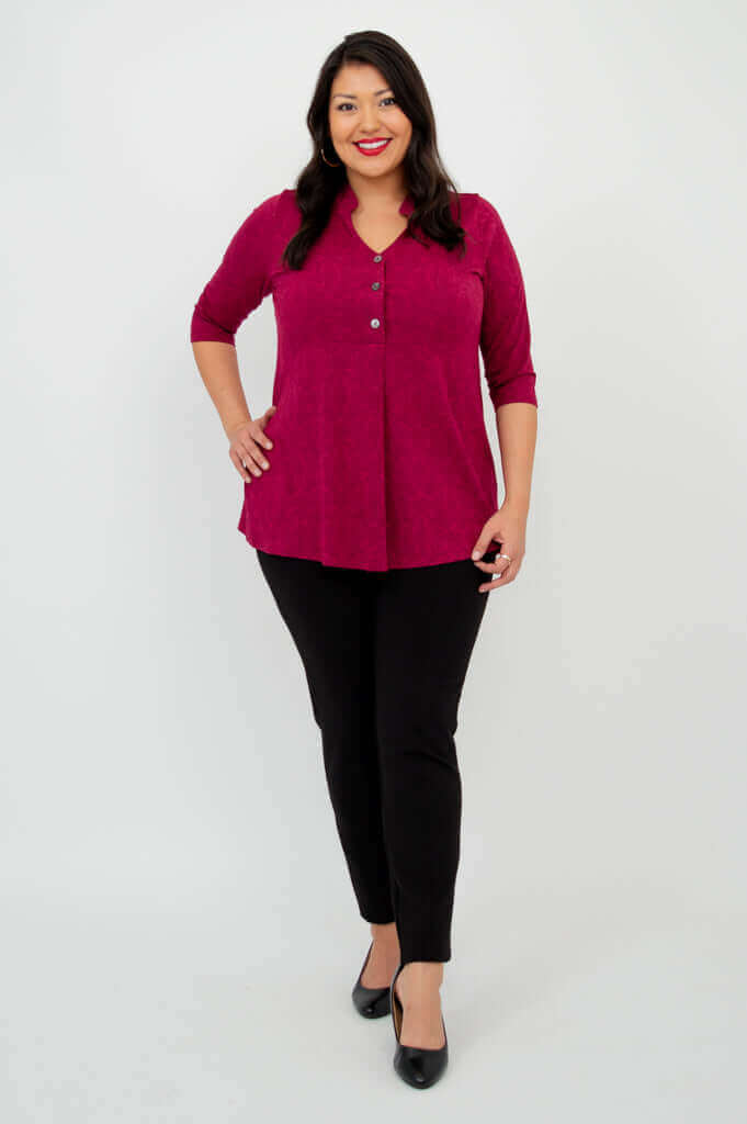Full body front view of woman in raspberry V-neck bamboo top with black pants and heels