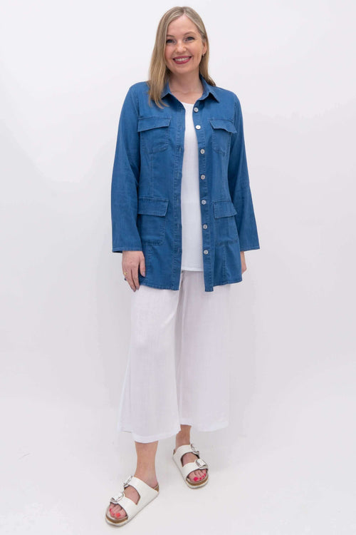 Full body view of woman in hip-length blue Kelly jacket paired with white pants