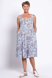 Woman in sleeveless paisley print dress with scoop neckline and pockets, full length