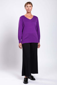 Full body shot of model in purple V-neck sweater and black wide-leg pants