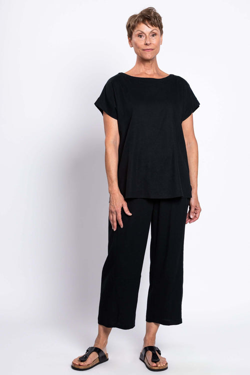 Full body view of a woman dressed in a black linen blend tee and matching black pants