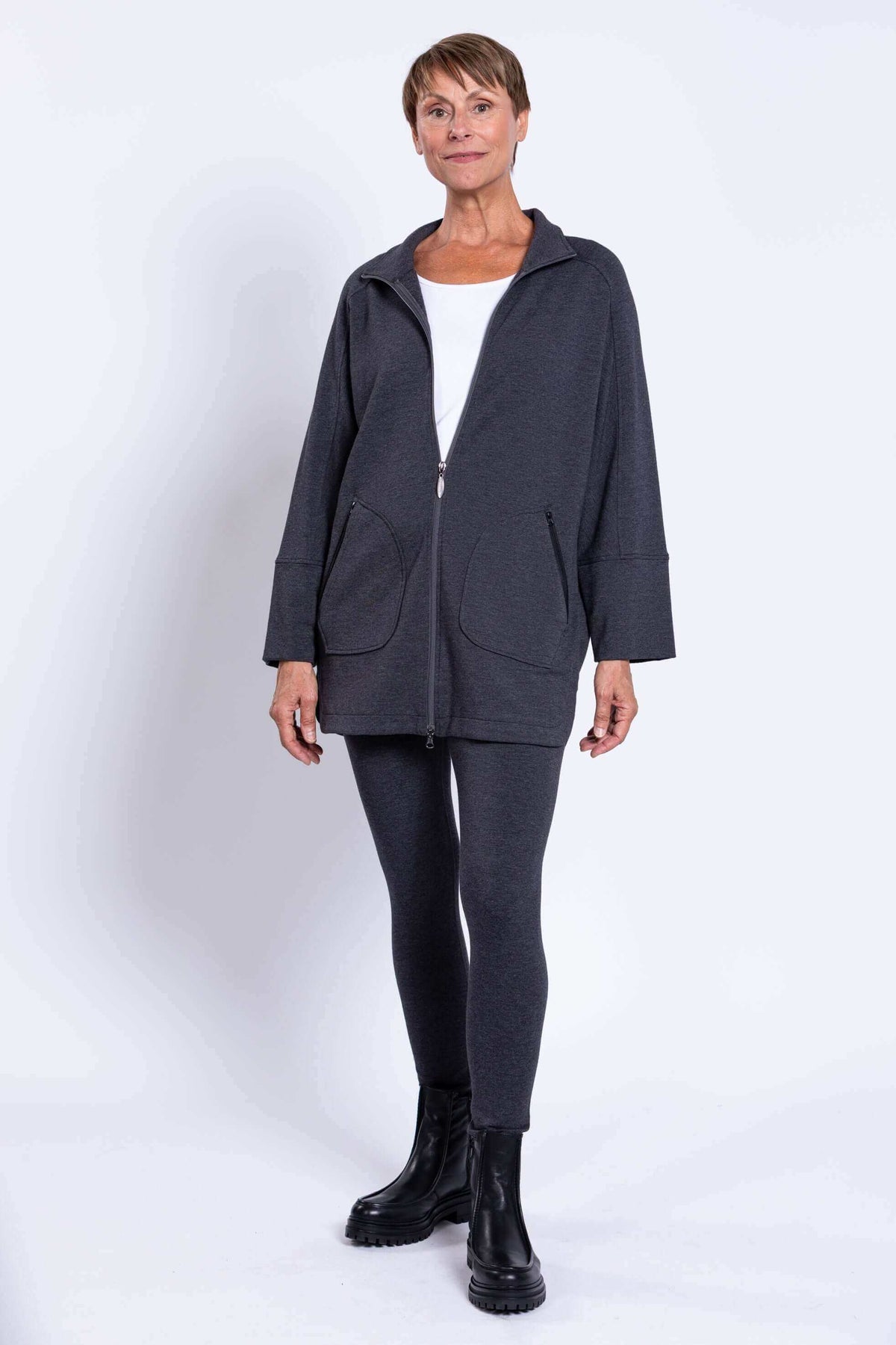Full body view of a woman in a dark grey zip-up jacket and matching leggings
