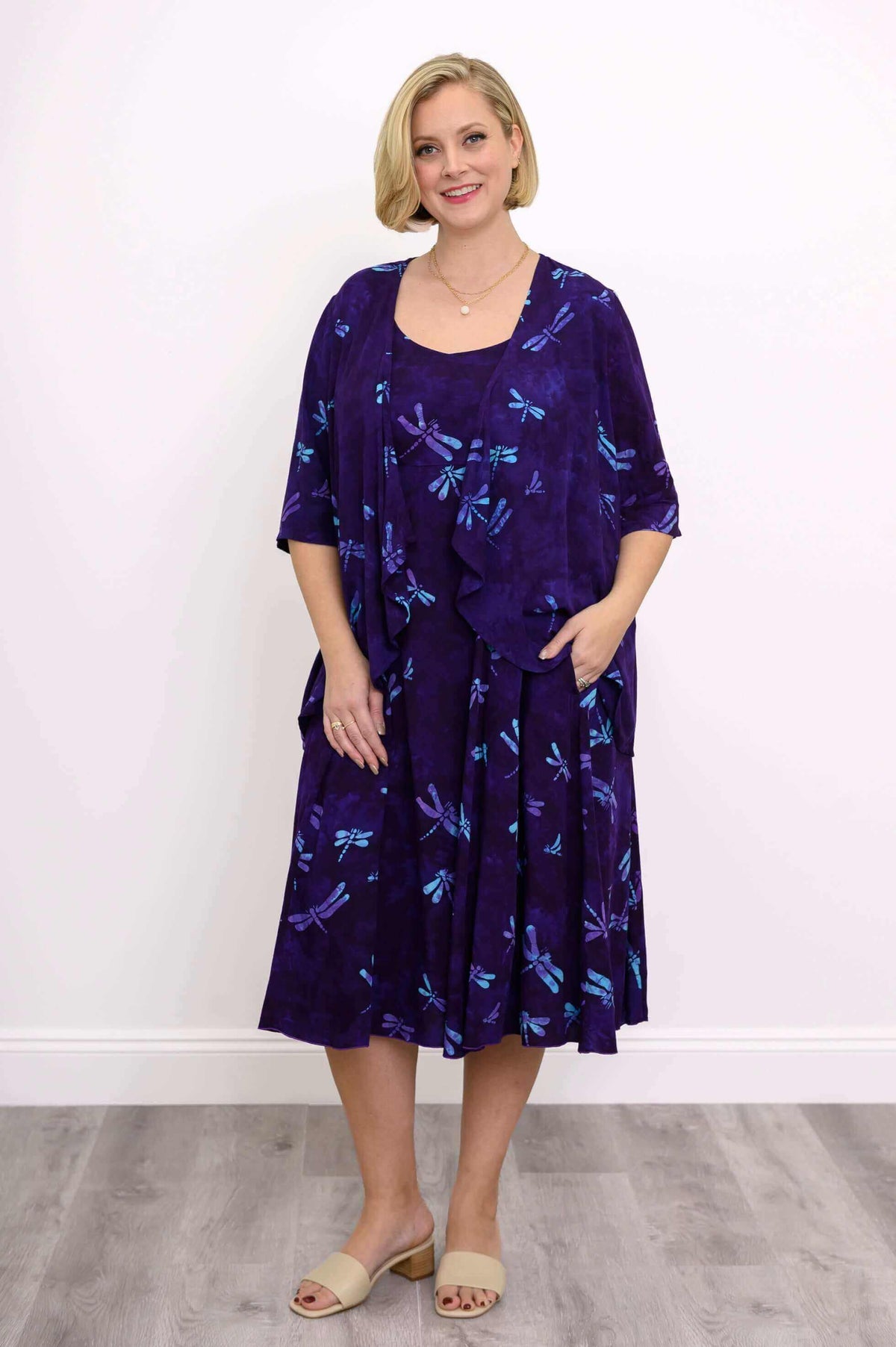 Full body view of woman in matching purple dragonfly print Toucan Jacket and dress