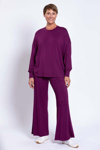 Full body view of woman in plum bamboo crew neck top and wide-leg pants