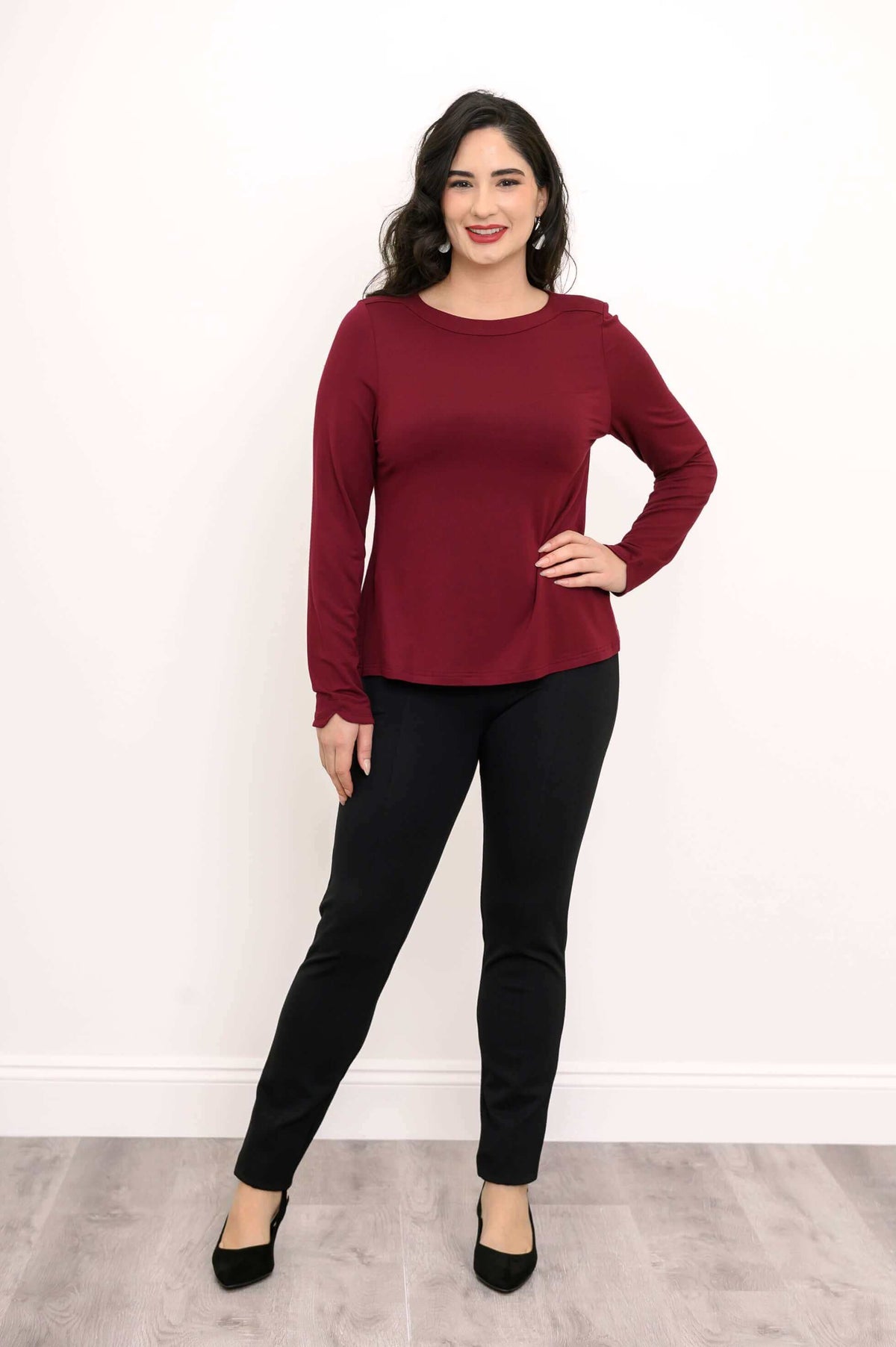 Full view of woman in merlot boat neck top with black pants and heels