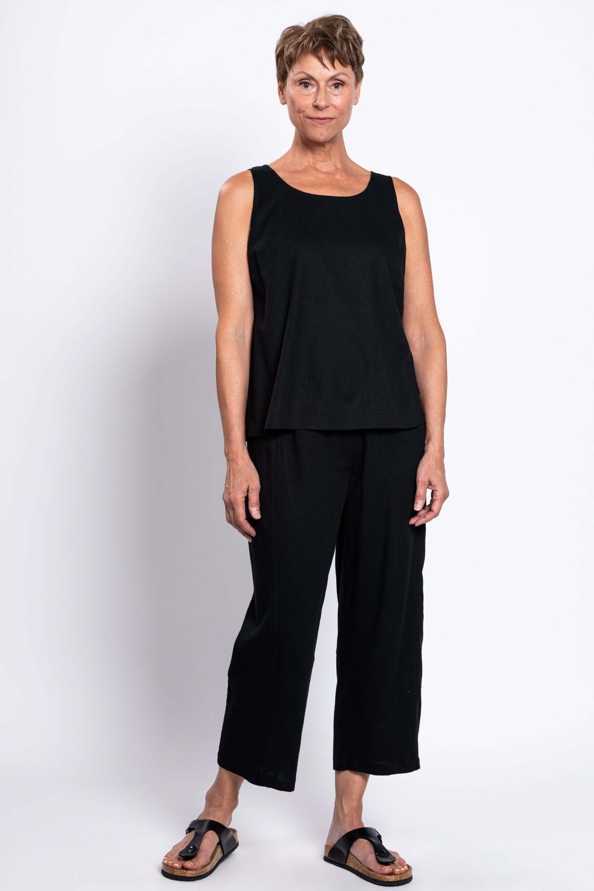 Full body front view of model in black sleeveless Ferris tank and pants