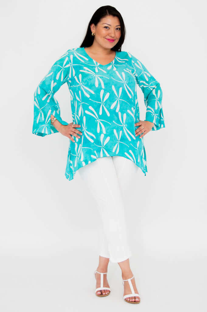 Full body view of model in aqua blue dragonfly print top and white pants