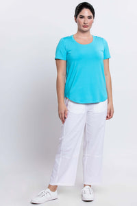 Full body view of model in aqua blue tee paired with white pants and sneakers