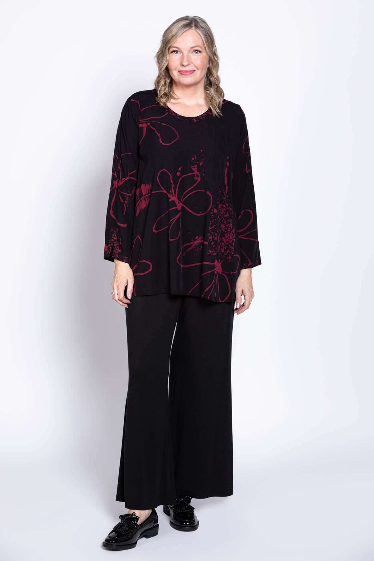 Full body view of model in black berry-print blouse and wide-leg pants