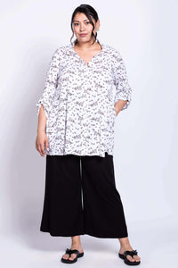 Full body view of model in petal print tunic and wide-leg black pants