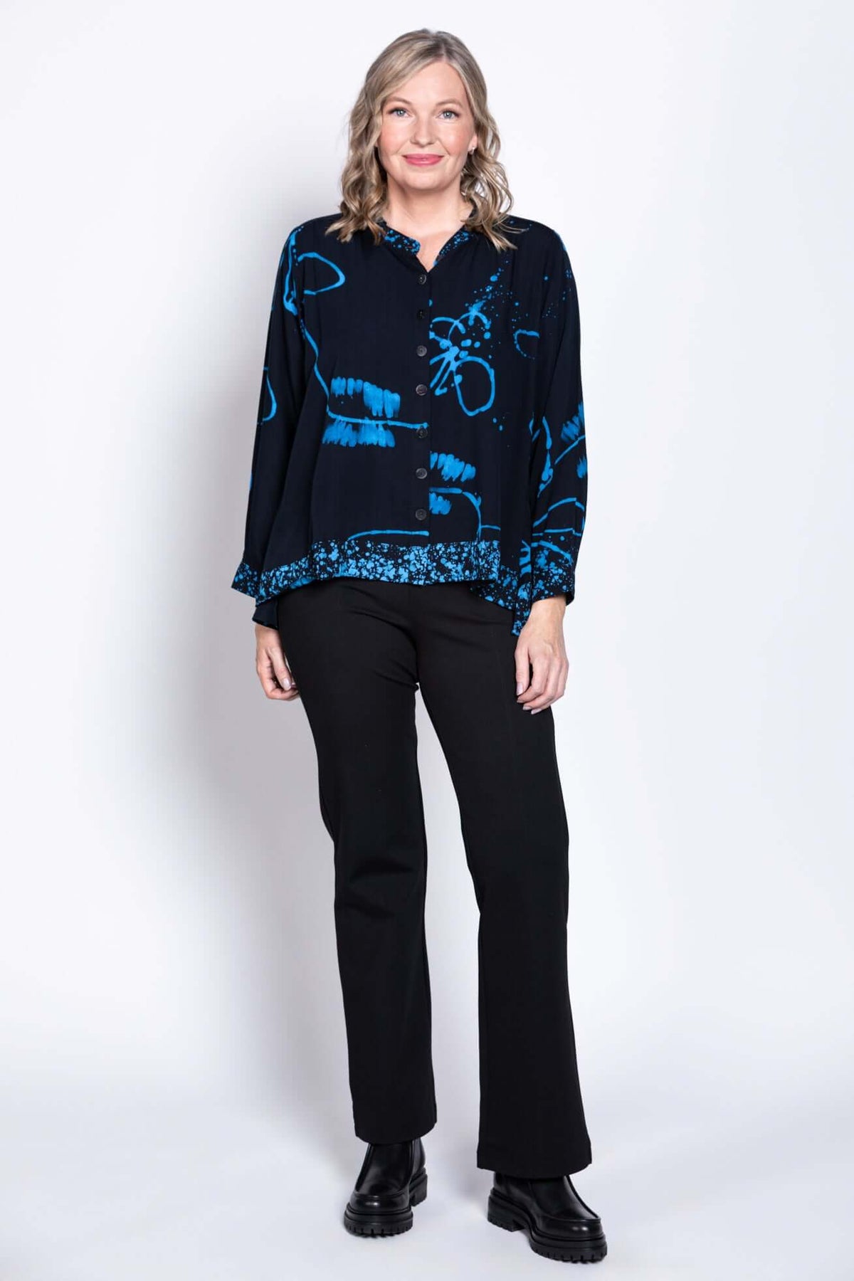 Full body view of a woman modeling a navy batik button-up blouse with black pants