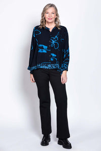 Full body view of a woman modeling a navy batik button-up blouse with black pants