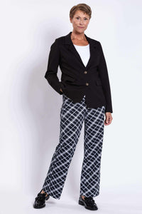 Full body view of woman in black blazer and checked pants with one hand in pocket