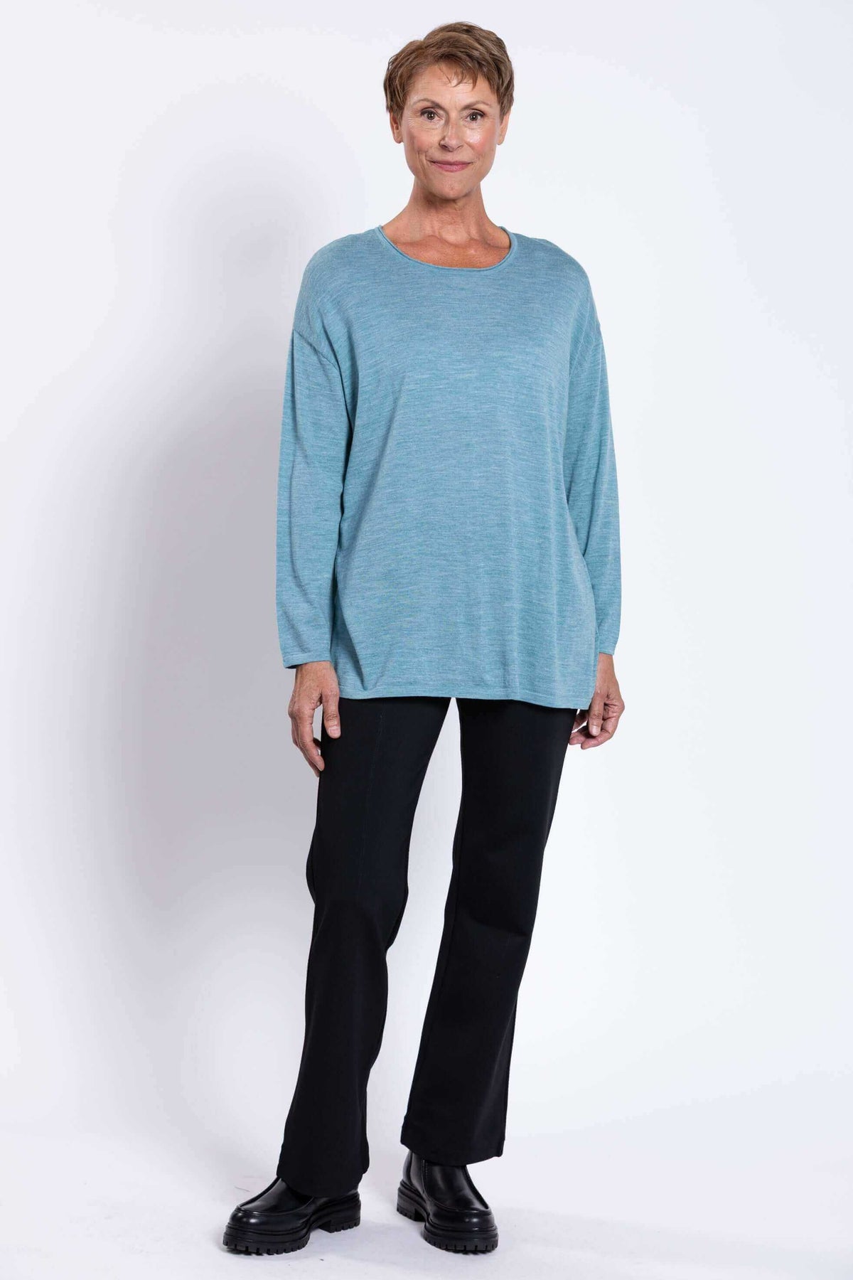 Woman showing full body view of blue Merino wool sweater with black pants