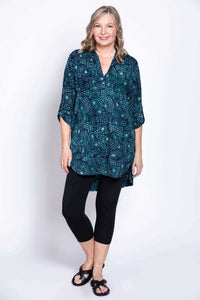 Full body view of woman in blue batik blouse, black leggings, and sandals