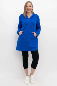 Full body view of woman in a blue hooded jacket, black leggings, and white sneakers