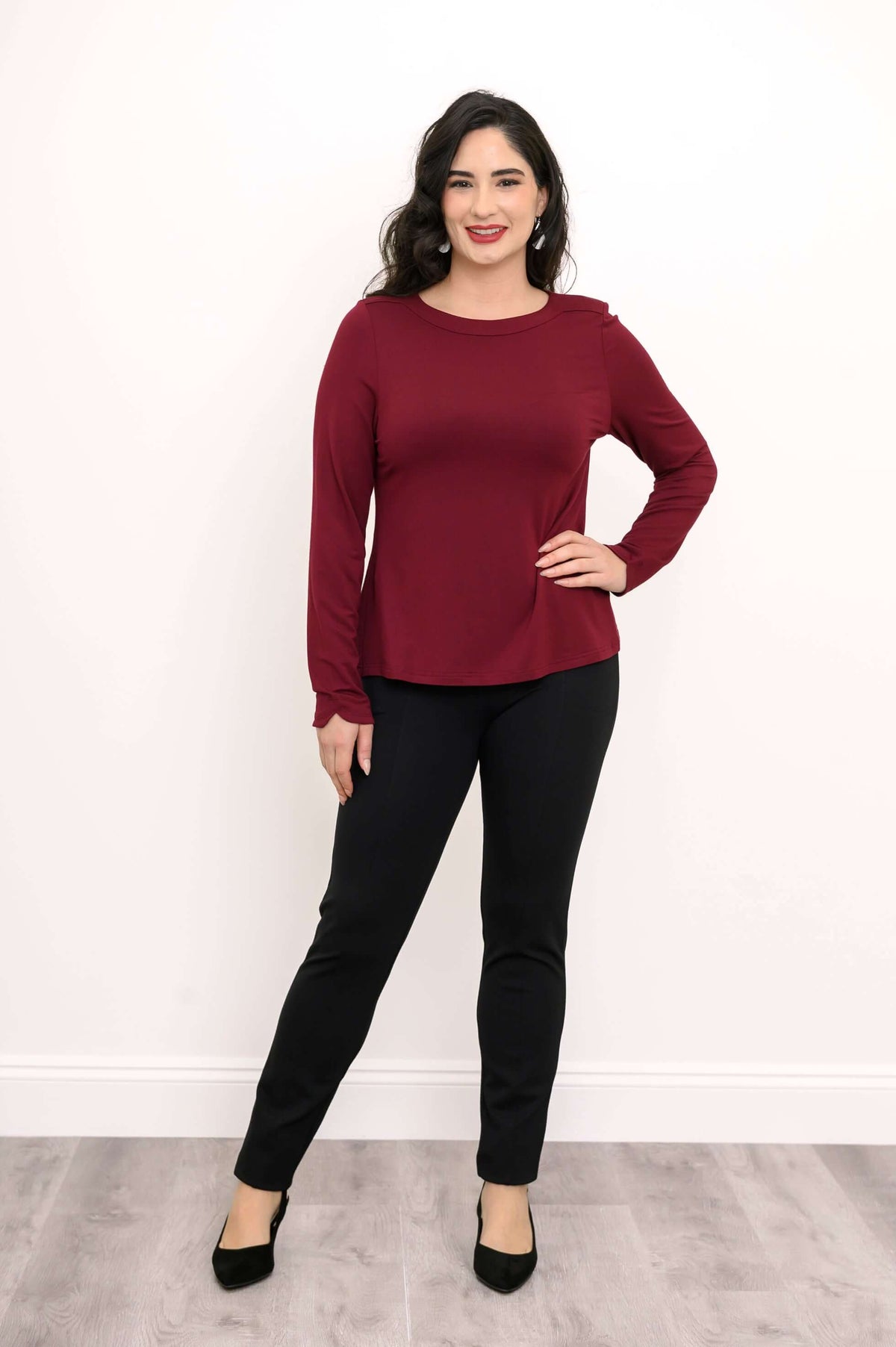 Full body view of woman in maroon boat neck top and black pants