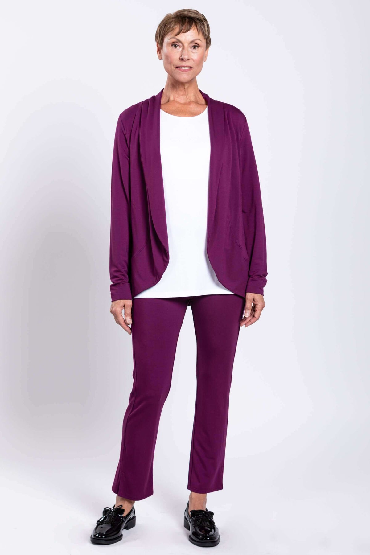 Full body view of woman in plum purple jacket and pants set with white top