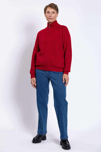 Full body view of a woman in a red zip-up cardigan sweater, blue jeans, and black boots