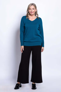 Full body view of woman in teal V-neck cotton sweater and black wide-leg pants