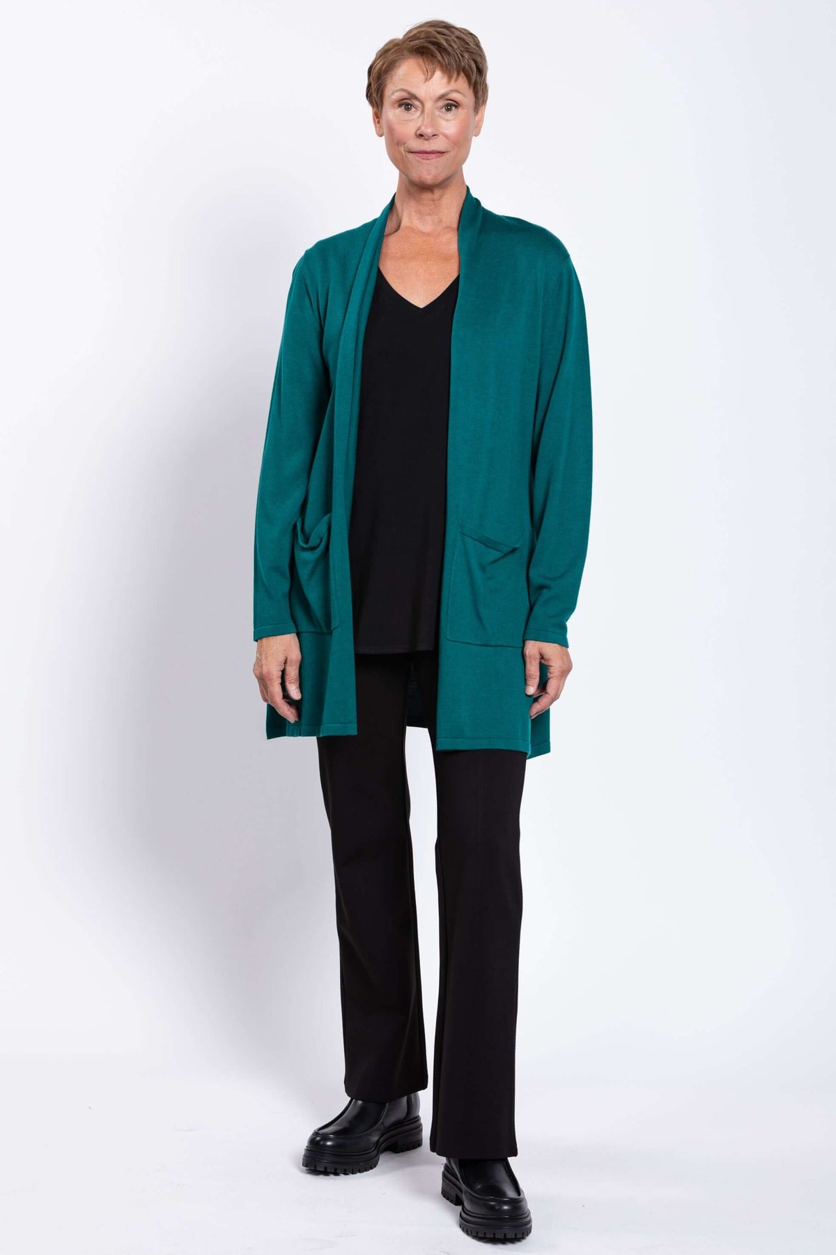 Full body view of woman in teal cardigan with patch pockets and black pants