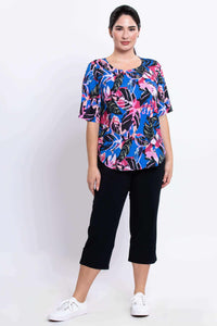 Full body view of woman in tropical print Liza blouse and black pants