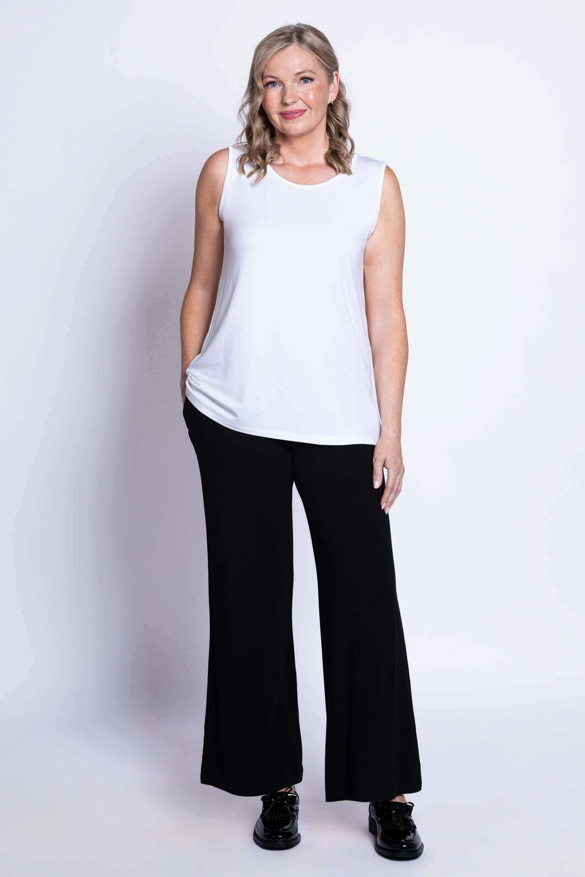Full body view of woman in white French Terry tank and black pants