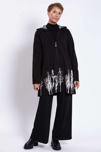 Full body view of woman modeling black Edith Coat with white tree border