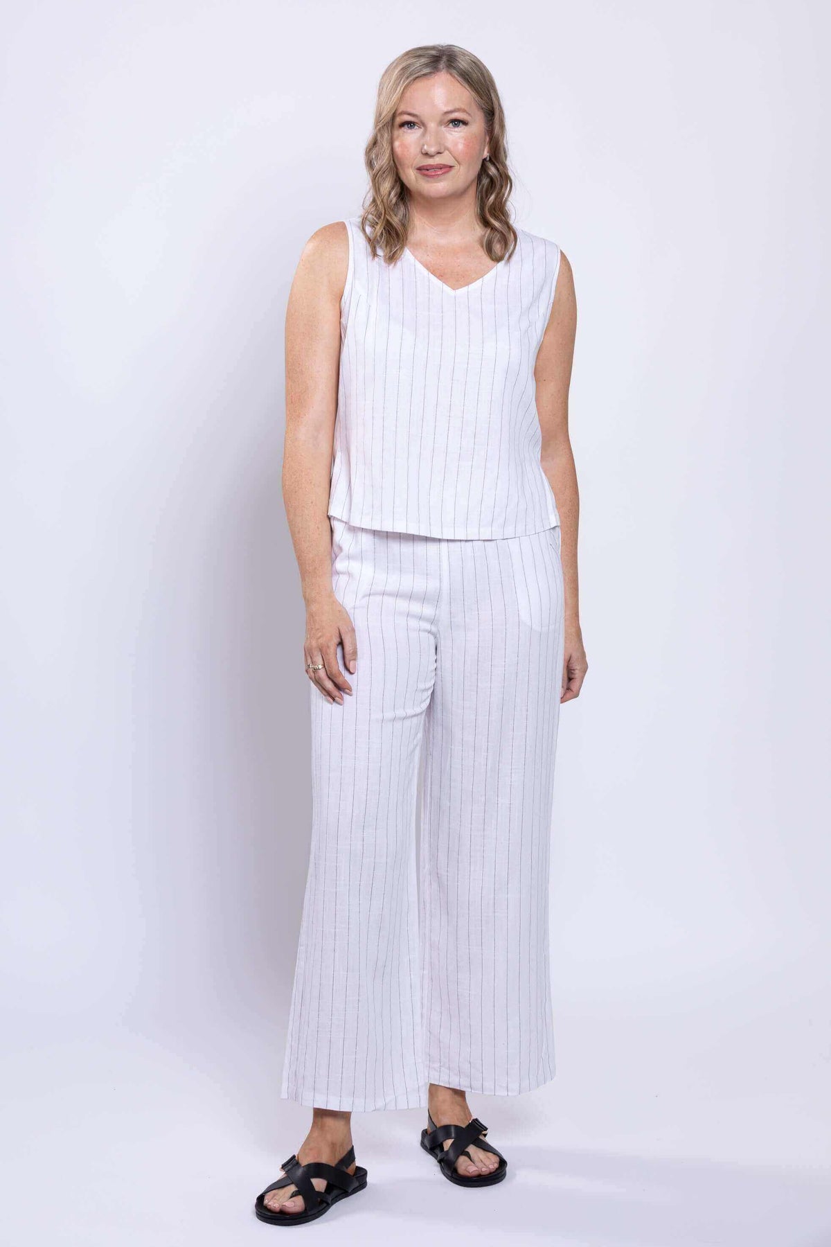 Full body view of woman wearing white striped linen blend cropped tank and wide leg pants