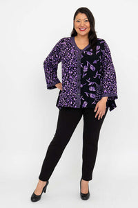 Full body view of model in black pants and black and purple patterned top