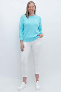 Full body view of woman in light blue sweater with white pants and sneakers
