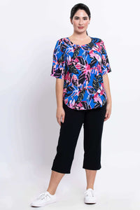 Full body image of model wearing half-sleeve tropical print blouse and black capri pants
