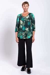 Full body front view of woman in green floral bamboo top and black wide leg pants
