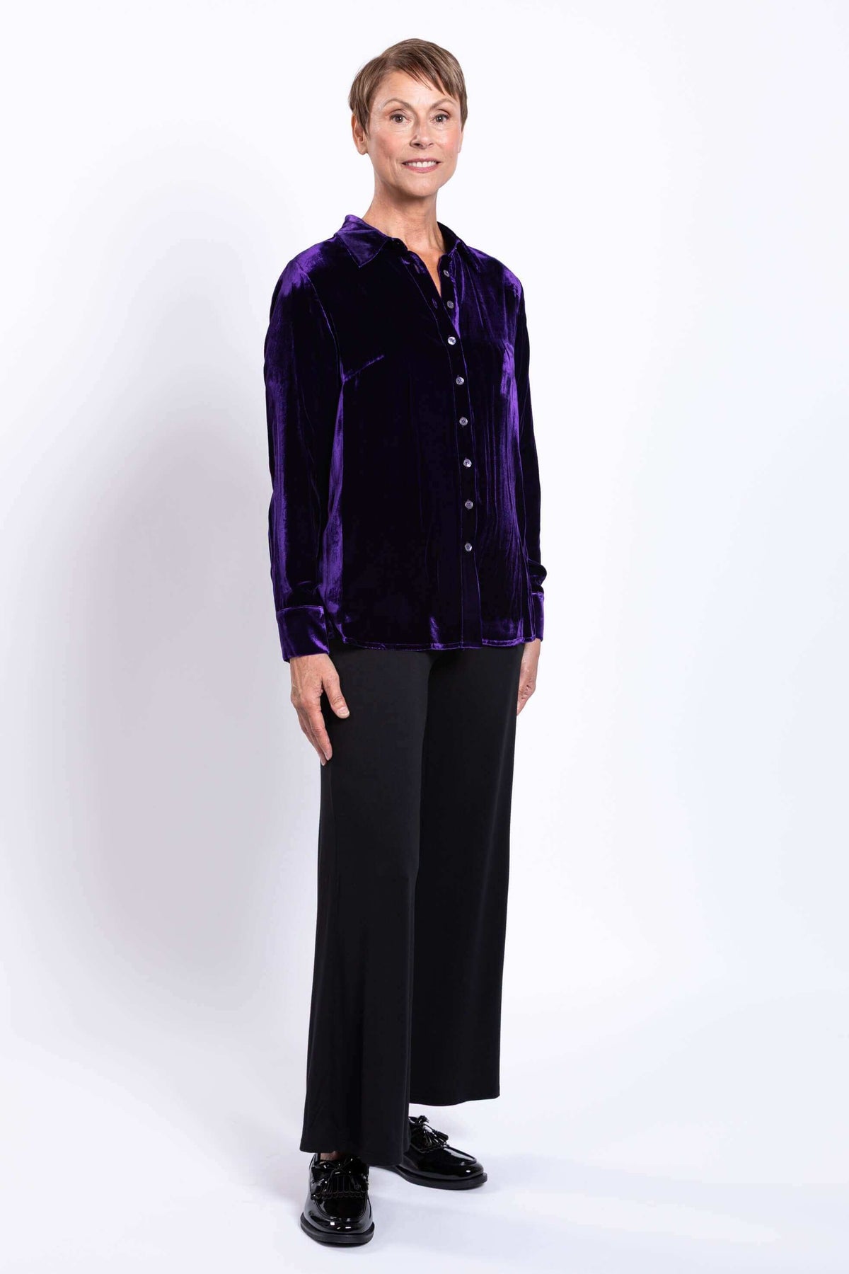 Woman modeling a deep purple velvet blouse and black pants, full front view