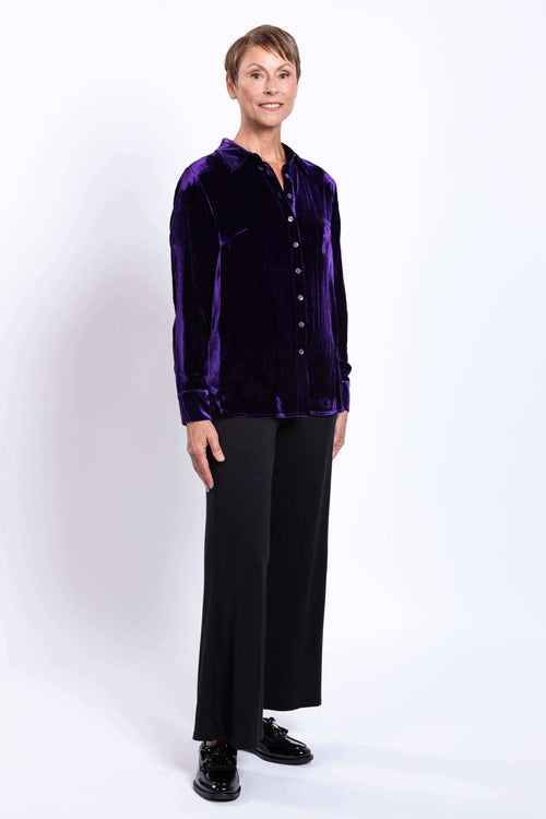 Woman modeling a deep purple velvet blouse and black pants, full front view