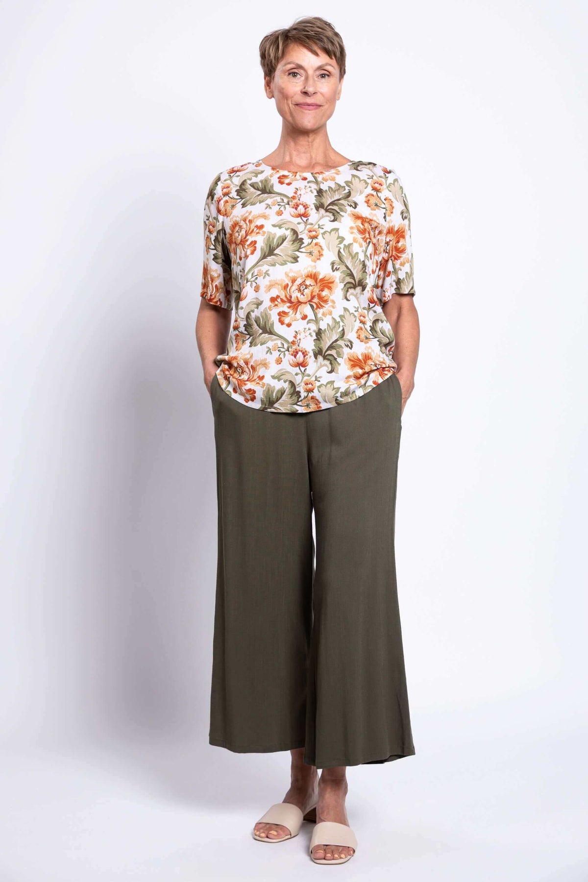 Full front view of woman in floral blouse and olive wide-leg pants