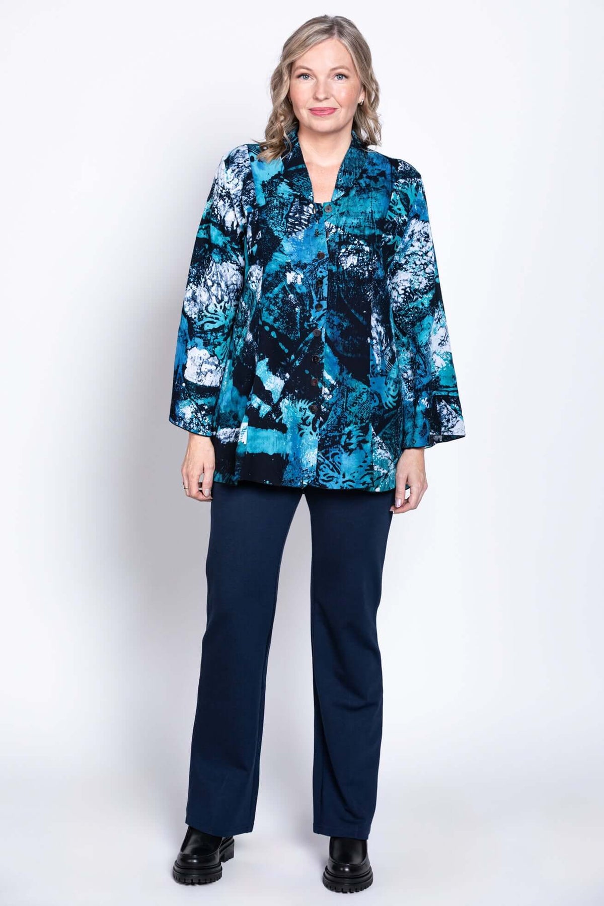 Full front pose of woman in Mar blouse with blue abstract pattern and navy pants