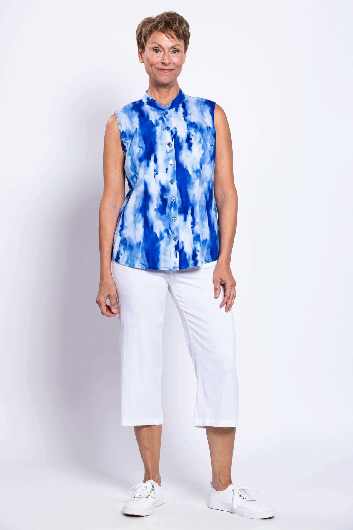 Full front view of a woman modeling a blue tie-dye sleeveless blouse with white pants