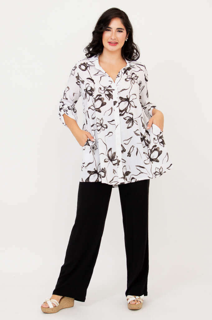 Woman modeling white floral bamboo linen tunic with hands in pockets, full front view