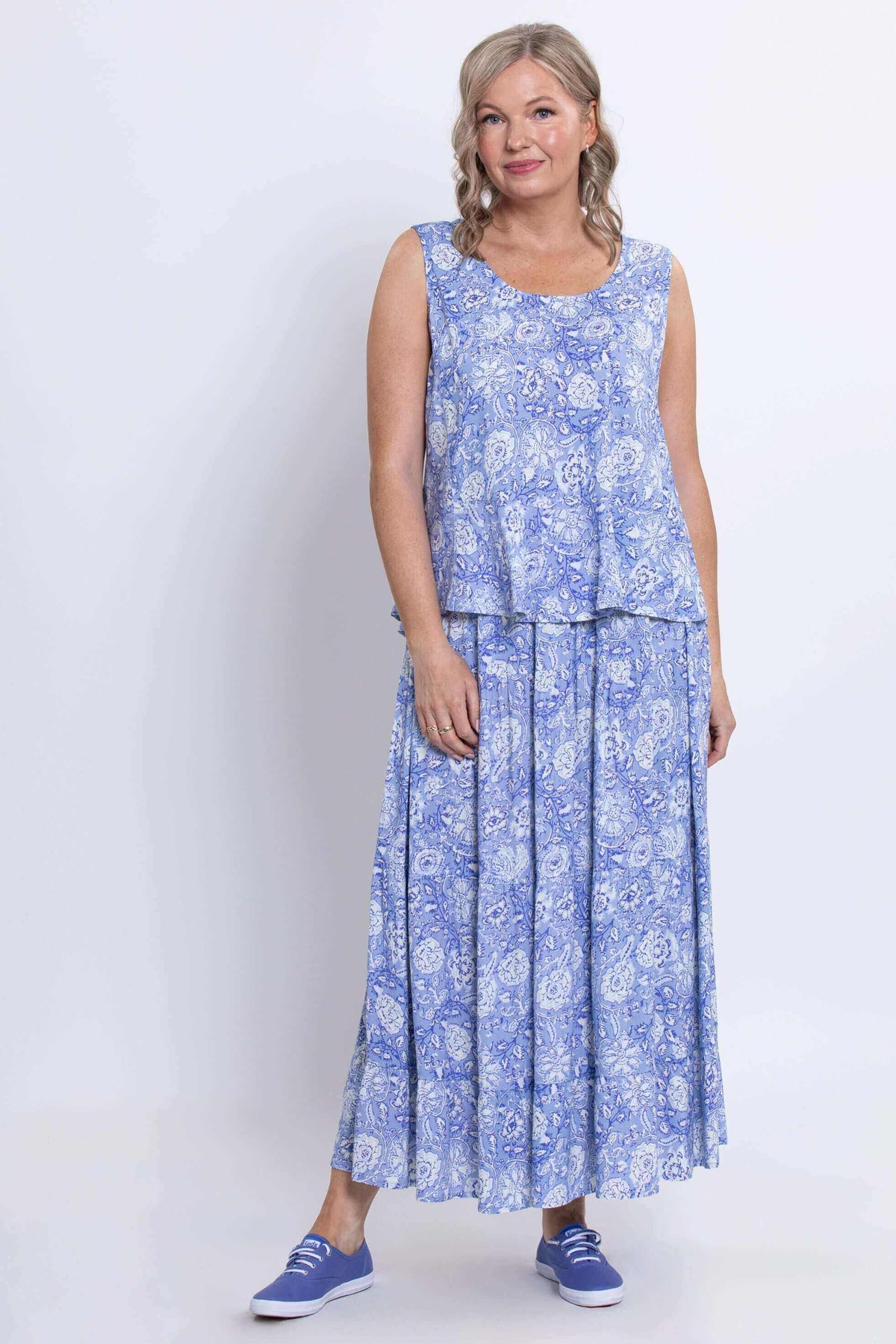 Full front view of model wearing a sleeveless peplum blue tank and matching skirt
