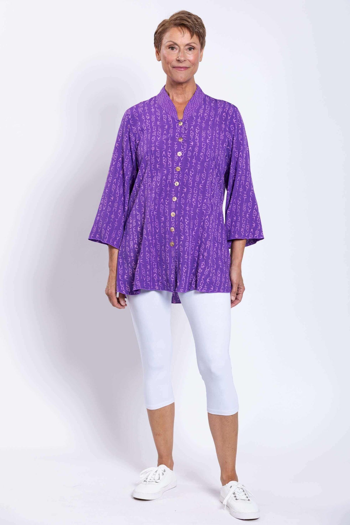 Full front view of model in violet Mar blouse with 3/4 bell sleeves and white capris