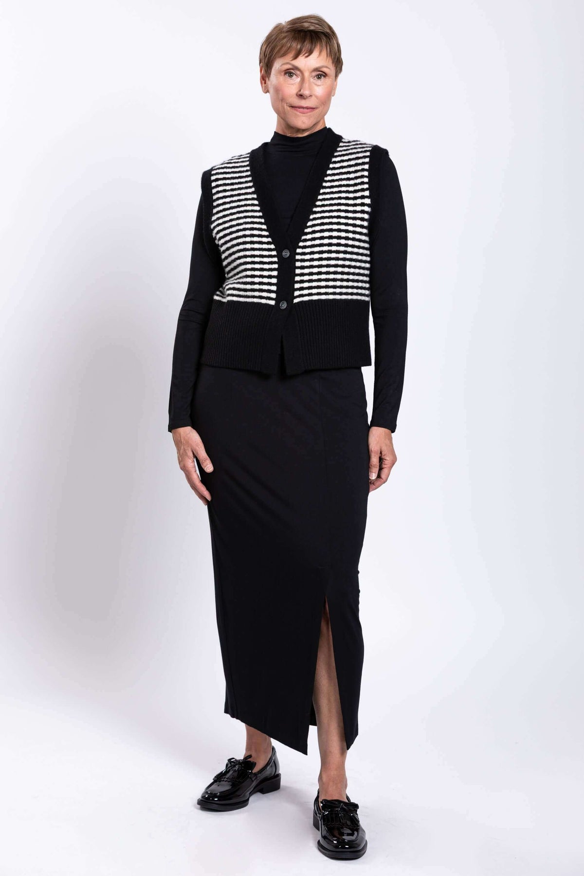 Full front view of a woman modeling a black and white striped vest with a black skirt