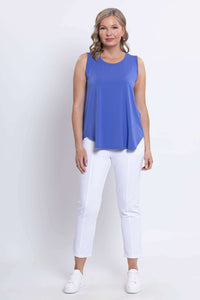 Full front view of a woman in an azure blue bamboo tank top paired with white pants and sneakers