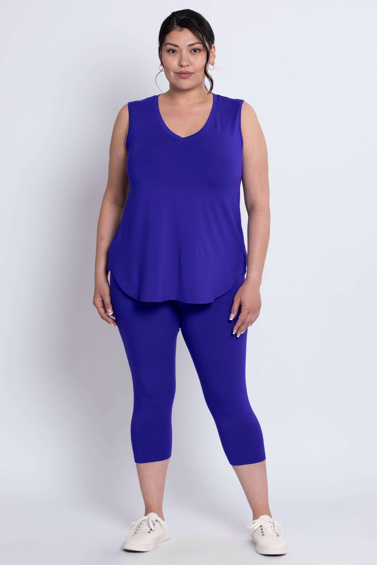 Model showing front view of blue capri leggings and matching sleeveless top
