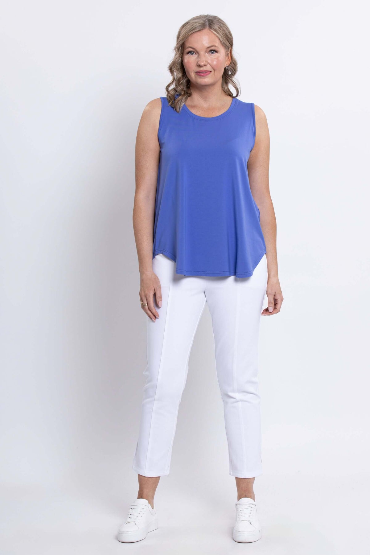 Full front view of woman in blue bamboo sleeveless tank top and white pants