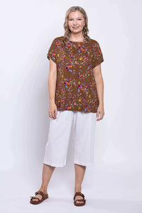 Woman in brown floral tee and white culottes, full front view