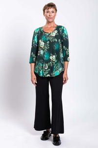 Full front view of a woman in a green floral bamboo top paired with black pants