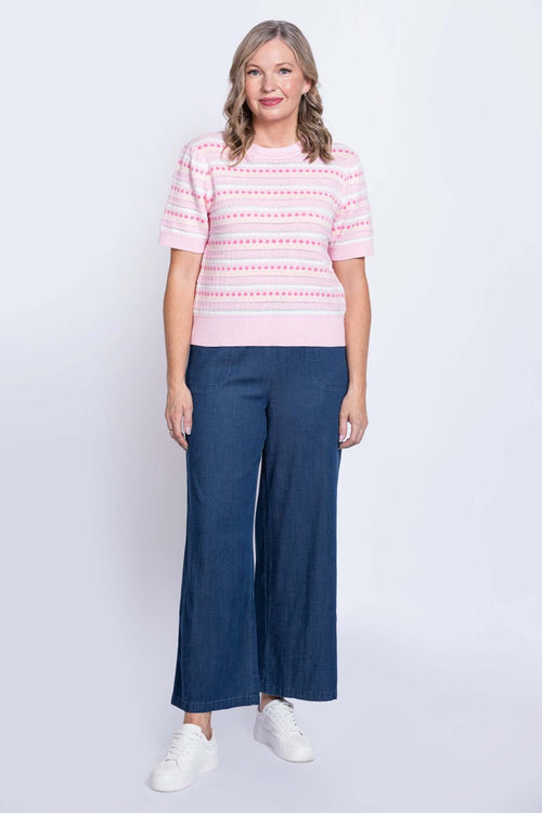 Full front view of woman in pink knit sweater and wide-leg jeans