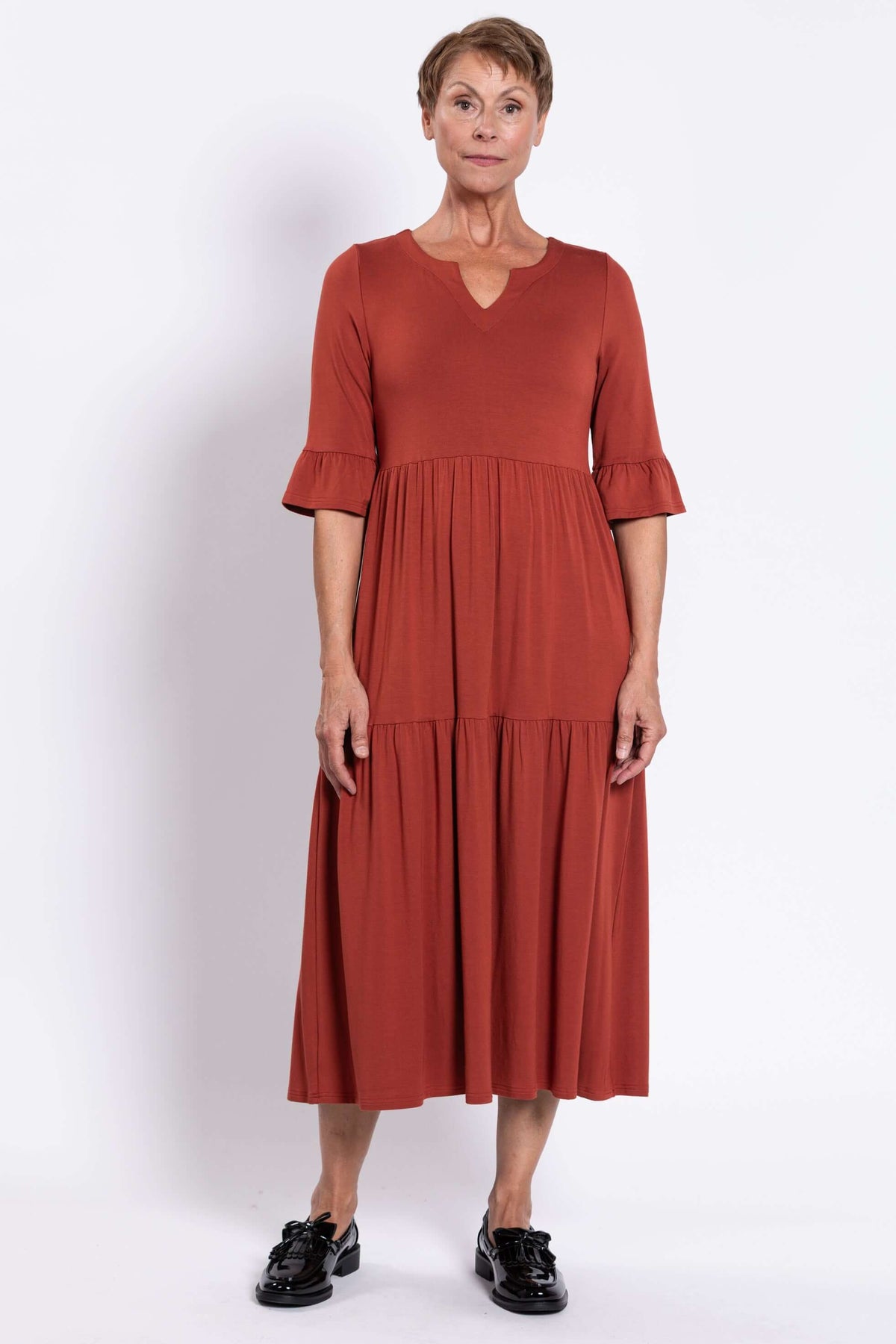 Full front view of model in rust midi dress with ruffle elbow sleeves